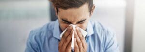 A man sneezes from allergies