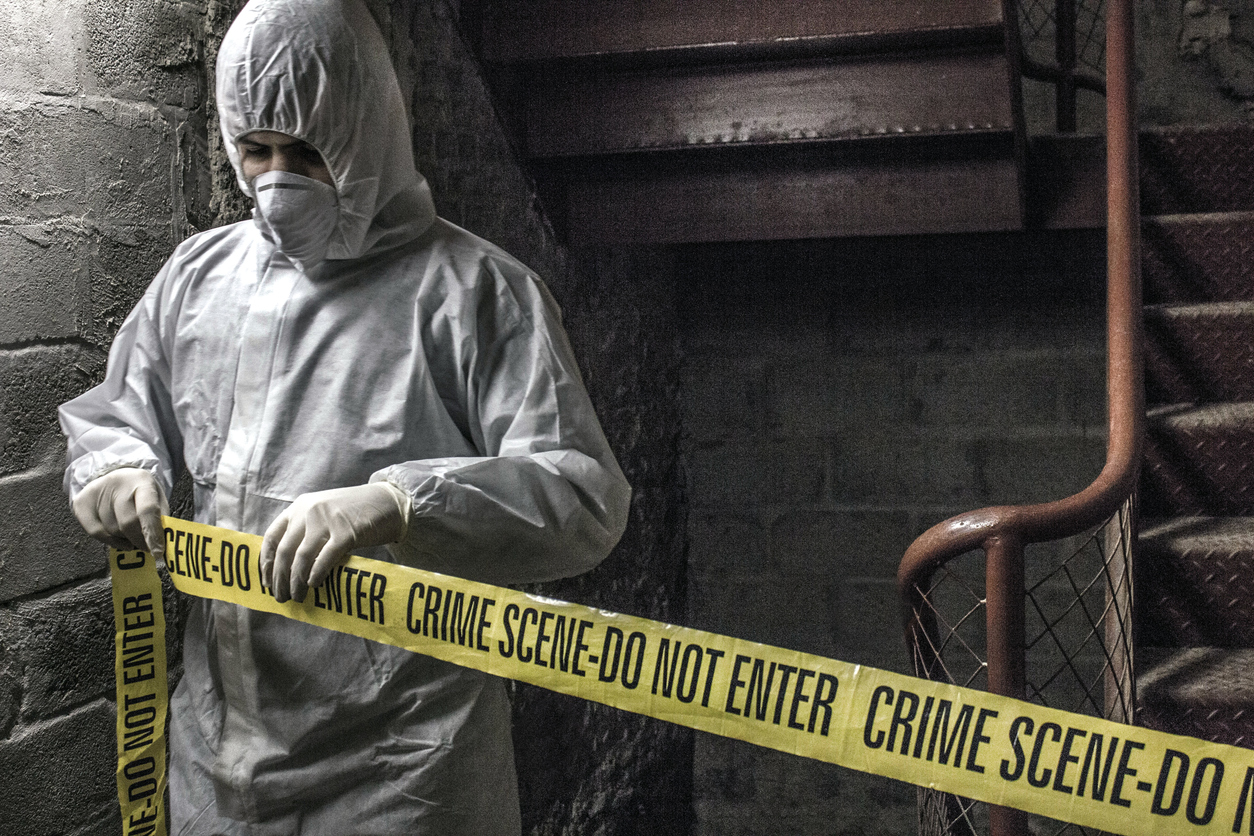 crime scene cleaner tying a dont cross ribbon on a crime scene.