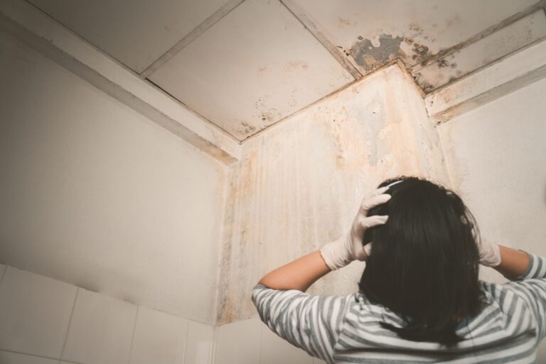 picture taken from behind woman got worried after seeing mold on the bathroom ceiling.